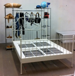 Lizzie Fitch (in collaboration with Lauren Boyle, Solomon Chase, and David Toro for DIS, Ryan Trecartin and Telfar Clemens), Pangea, 2010. Bed Frame, wood, windows, clothing, printed material, globe, purses, belts, rocks, sand, paint, clothing rack, plaster, foundation, nails, gloves, eyelashes, pillows, shoes, hangers, video cameras, hammer, tupperware, clothespin, plastic, dimensions variable. Courtesy The New Museum