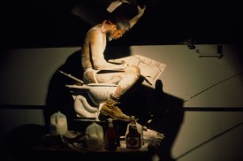 Pope L. performing Eating the Wall Street Journal (2000) at The Sculpture Center, New York, 2000. Courtesy of the artist. Photo: Lydia Grey. Installation on view at Grey Art Gallery, NYU.