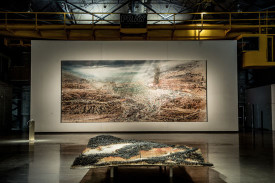 Dominique Gaucher, foreground Plantation, 2014. Wood, metal and matches, 36 x 120 x 180 inches and hanging, Delta, 2011-2012. Acrylic, oil and paper on canvas, 180-1/4 x 422 inches. Courtesy of Arsenal, Montreal