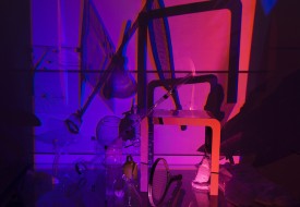 Blinn & Lambert, Untitled (Broom, Out), 2017. Multiple found glass objects, Mylar sculptures, Styrofoam sculptures, rubber ball, tennis racquet, drawing on glass, fabric, magnifying glass, glass table, steel legs, two video-projectors, 82 x 80 x 84 inches. Courtesy of the artists and Microscope Gallery
