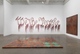 Installation shot of the exhibition under review, with works by Nari Ward: “We the People,” 2011; “Ground (In Progress),” 2015; “Breathing Panel: Oriented Center,” 2015.. Image courtesy of the New Museum. Maris Hutchinson/EPW Studio